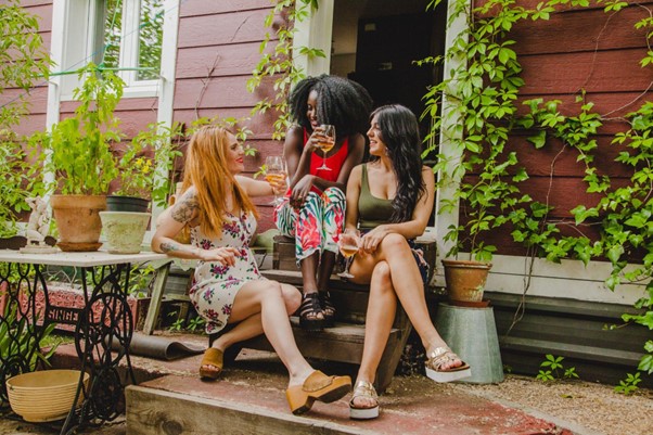 [Obrázek: Tři ženy sedí na schodech domu, vychutnávají nápoje a povídají si. Jsou obklopeny rostlinami a zelení. (freepik)]