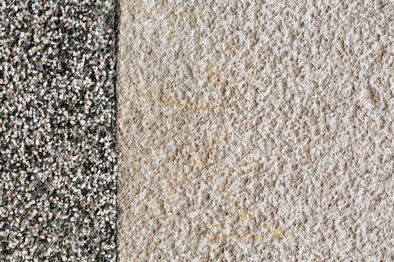Detailní záběr dvou povrchů podlahy: vlevo kamenný koberec z malých oblázků, vpravo drsný omítkový nebo betonový povrch.