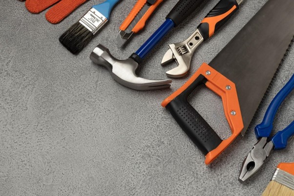 [Obrázek: Různé ruční nářadí jako kladivo, pila, klíč a kleště na šedém povrchu. (freepik)]