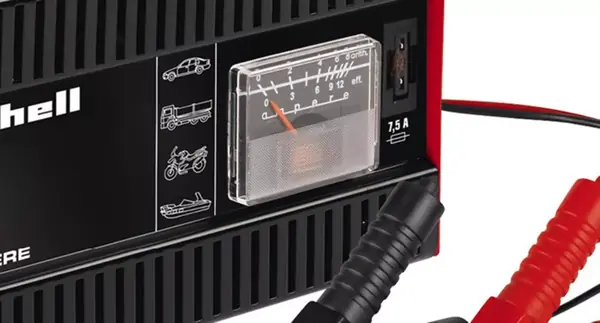 Detail nabíječky Einhell CC-BC 5 s analogovým ukazatelem, ventilační mřížkou a připojenými svorkami.