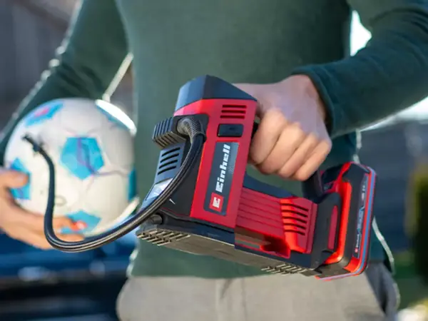 Osoba nafukuje fotbal pomocí aku kompresoru na auto Einhell CE-CC 18/23 D Li-Solo.