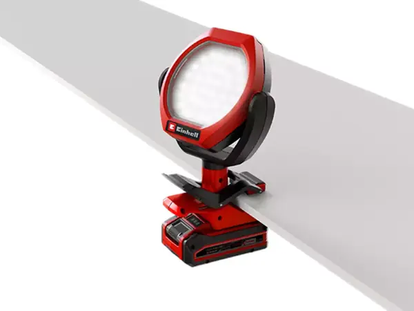 Aku venkovní lampa Einhell GC-OL 18/1500 Li-Solo je umístěna na bílém okraji stolu a mírně nakloněná směrem dolů.