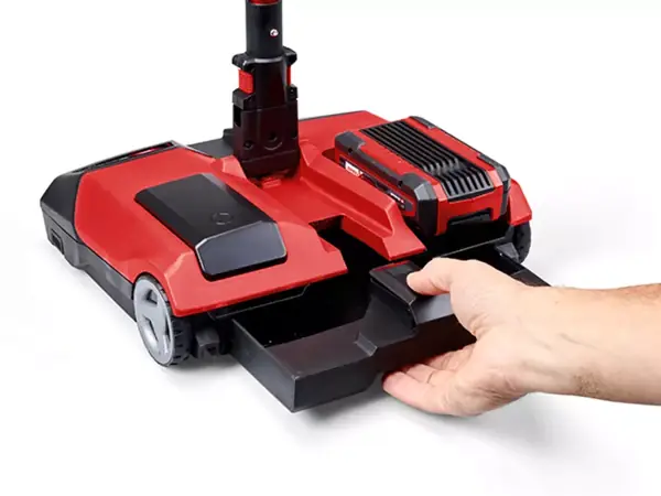 Az Einhell TE-FS 18 Li akkumulátoros seprűje fehér háttér előtt; egy kéz leveszi a gyűjtőtartályt.