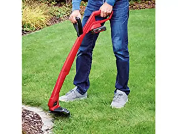 Aku sekačka na trávu Einhell GC-CT 18/24 Li P (1x1,5 Ah) v provozu, vedená osobou podél okraje trávníku.