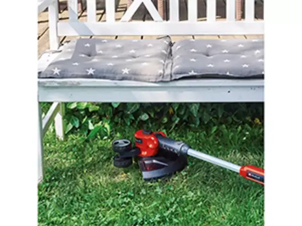 Aku vyžínač Einhell GE-CT 18/30 Li-Solo při práci pod zahradní lavicí při zastřihování obtížně přístupných míst trávníku.