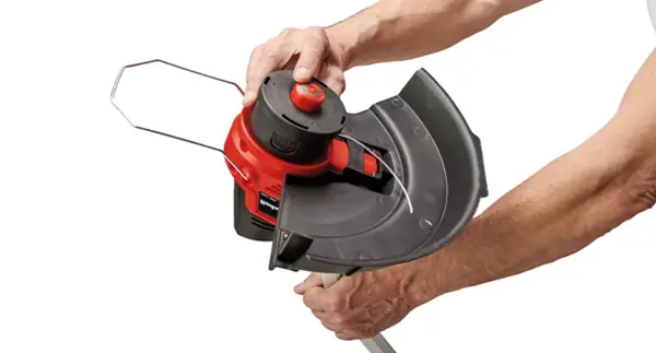 Eine Person zeigt die Fadenspule mit Tippautomatik des Einhell Akku-Rasentrimmers GE-CT 18/33 Li E bei der Bedienung.