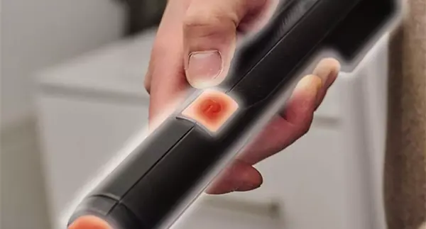 Rukojeť teleskopické tyče s označeným, červeně podsvíceným vypínačem.