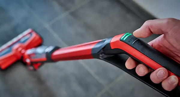 Detailní záběr na rukojeť akumulátorového čističe tvrdých podlah Einhell CLEANEXXO se zeleně svítícím LED displejem a tlačítkem pro nastavení rychlosti otáčení.