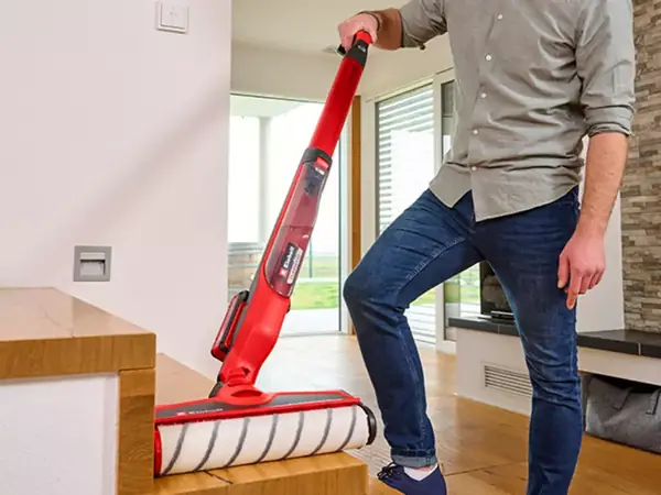 Akumulátorový čistič tvrdých podlah Einhell v provozu s viditelným flexibilním kloubem u okraje schodu.