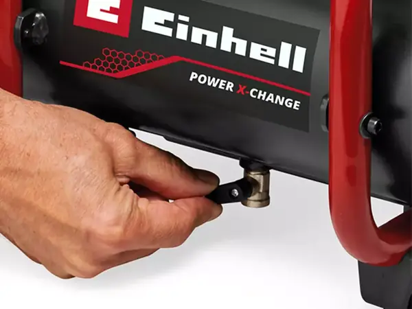 Eine Hand bedient das Entwässerungsventil am unteren Teil des Einhell Akku-Kompressors.