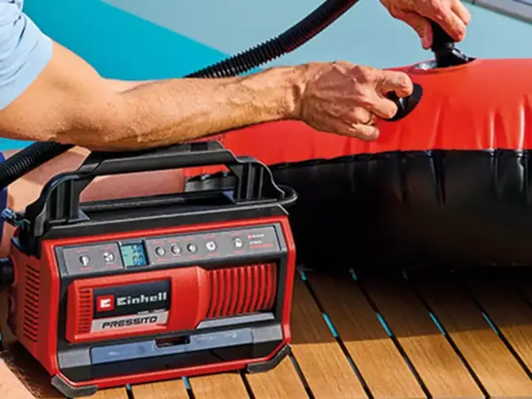 Nahaufnahme des Einhell Akku-Kompressors PRESSITO 18/25 Hybrid beim Anschluss an ein Ventil eines Schlauchboots.