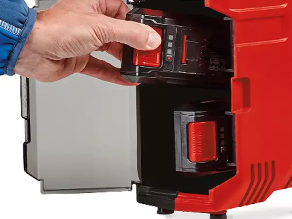 Hand setzt einen Akku in das seitliche Fach des Kompressors ein.