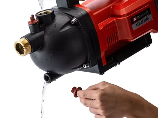Ruka otevírá vypouštěcí šroub na zahradním čerpadle Einhell AQUINNA 36/30, z něhož vytéká voda.