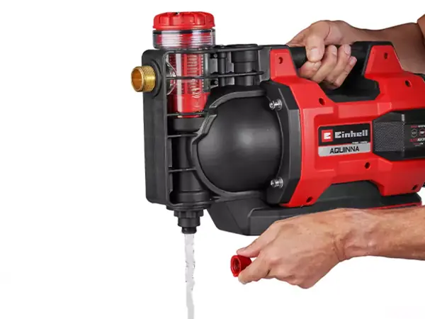 Ein Mann öffnet die Wasserablassschraube an der Einhell Akku-Gartenpumpe AQUINNA 18/30 F LED AUTOMATIC.