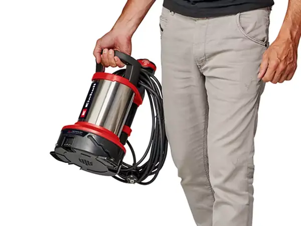 Mężczyzna trzyma pompę do wody brudnej Einhell GE-DP 7535 N LL ECO za uchwyt, urządzenie zwisa w dół.