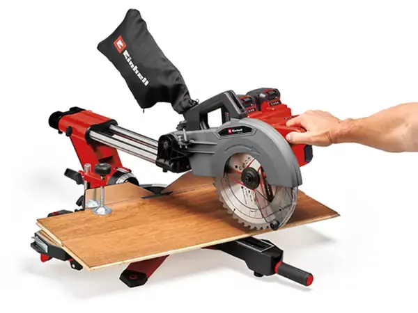 Ruka používá posuvnou funkci bezkabelové posuvné pokosové pily Einhell TE-SM 36/10 L Li k řezání dřevěné desky.