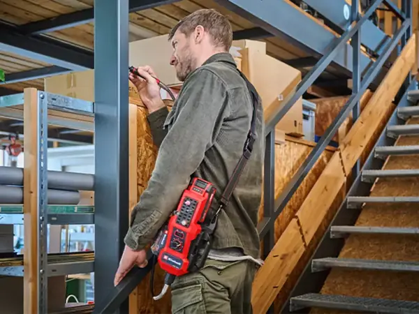 Muž s popruhem přes rameno nese akumulátorový brusný a gravírovací nástroj Einhell TE-MT 18/34 Li.