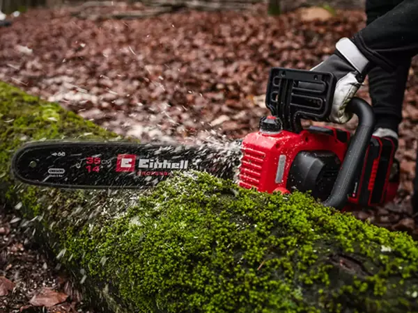 Při řezání ležícího kmene odletují jasně viditelné dřevěné třísky.