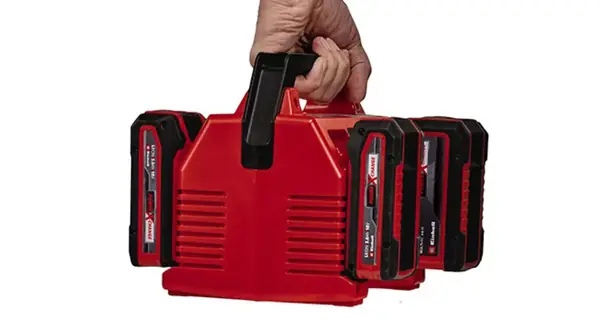 Einhell Power X-Quattrocharger 4A je držen v jedné ruce za madlo se čtyřmi vloženými akumulátory.