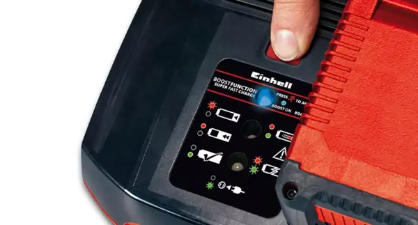 Prst tiskne tlačítko boost na nabíječce Einhell Power X-Boostcharger 8A, ve které je vložena baterie.