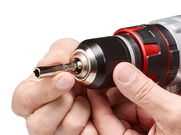 Ruka vkládá vrták do kovového sklíčidla aku-příklepové vrtačky.