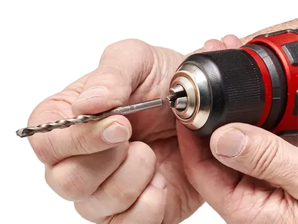 Dvě ruce nasazují vrták do sklíčidla aku příklepového šroubováku Einhell.