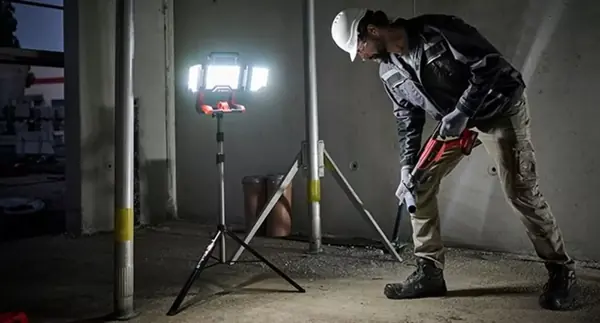 Stavební dělník osvětluje staveniště ve tmě pomocí akumulátorové lampy Einhell TP-CL 18/3000 Li - Solo na stativu.