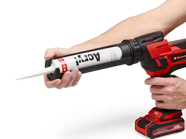 Aku pistole na kartuše Einhell s vloženou akrylátovou kartuší, otočný držák kartuše je držen rukou.