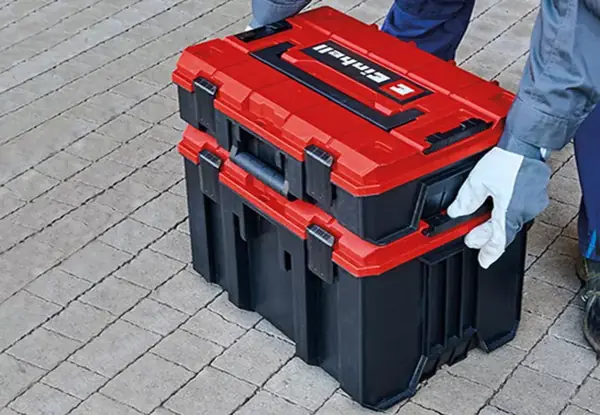 Systémový kufr Einhell E-Case M s otevřeným uzamykacím systémem na dlážděném povrchu.