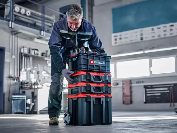 Muž umisťuje nářaďový kufr Einhell E-Case na pojízdný kufr.