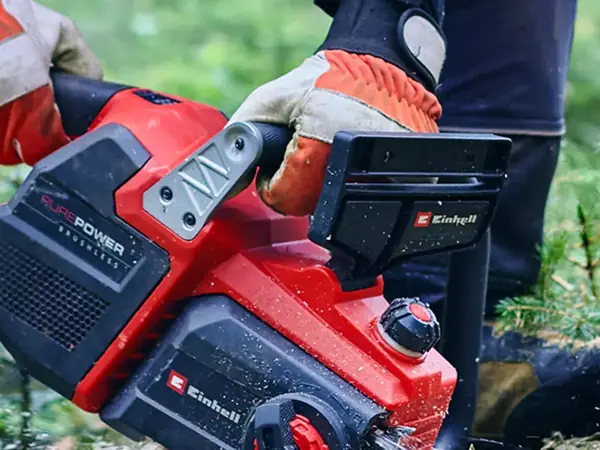 Osoba drží aku řetězovou pilu Einhell GP-LC 36/40 Li BL-Solo oběma rukojeťmi na zahradě.
