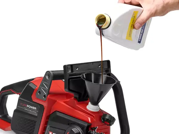 Ruka nalévá olej do olejové nádrže aku řetězové pily Einhell GP-LC 36/40 Li BL-Solo na bílém pozadí.