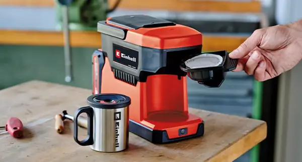 Eine Person setzt den Einsatz mit einem Kaffeepad in die Einhell Akku-Kaffeemaschine TE-CF 18 Li ein.